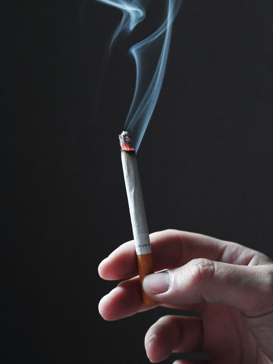 Hand holding a burning cigarette — quit smoking